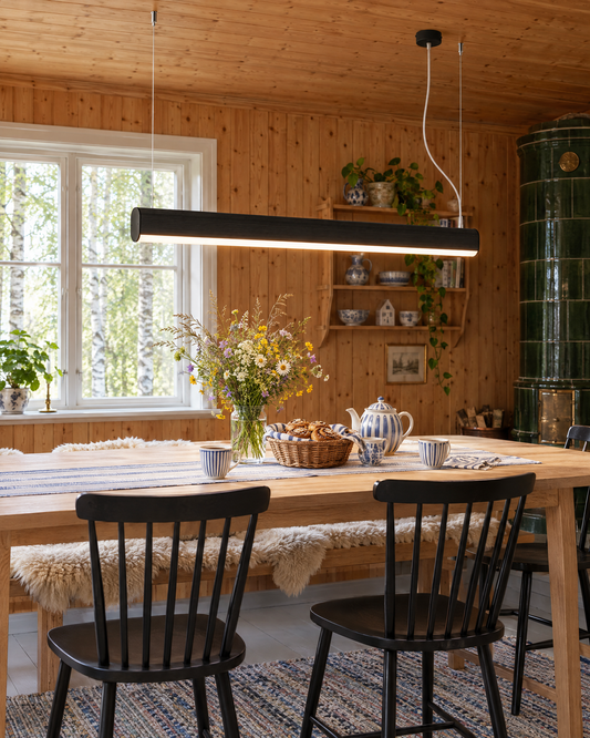 Suspension Farge noire au-dessus d'une table en chêne dans une salle à manger scandinave en pin