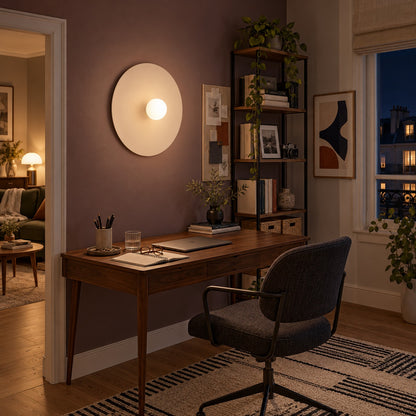 Applique Ake beige allumée au-dessus d'un bureau le soir