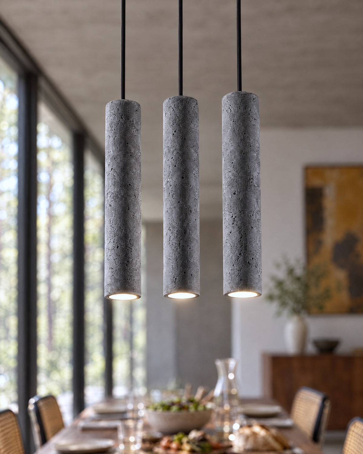 Détail des trois cylindres en béton de la suspension Luvo dans une salle à manger