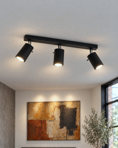 Détail des trois spots orientables noirs du plafonnier Ring dans un salon
