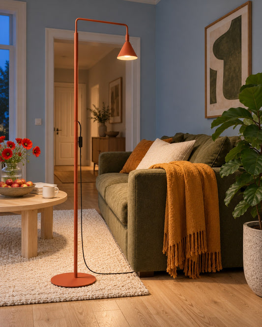 Lampadaire Nox ocre rouge allumé le soir près d'un canapé dans un salon