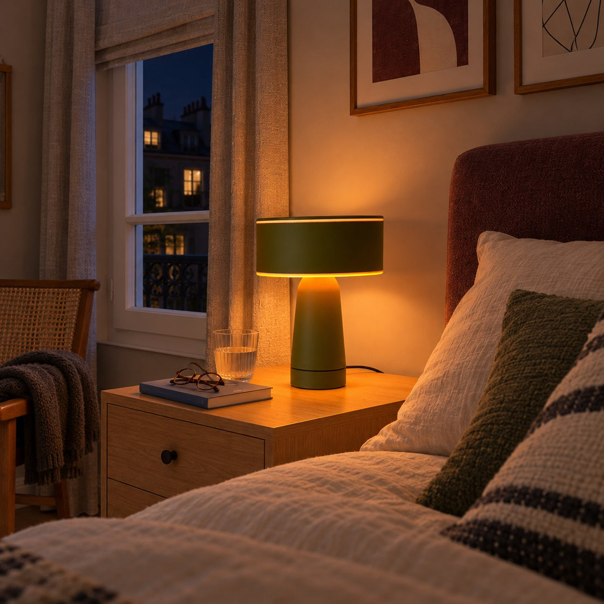 Lampe Axo vert olive allumée sur une table de chevet, vue rapprochée