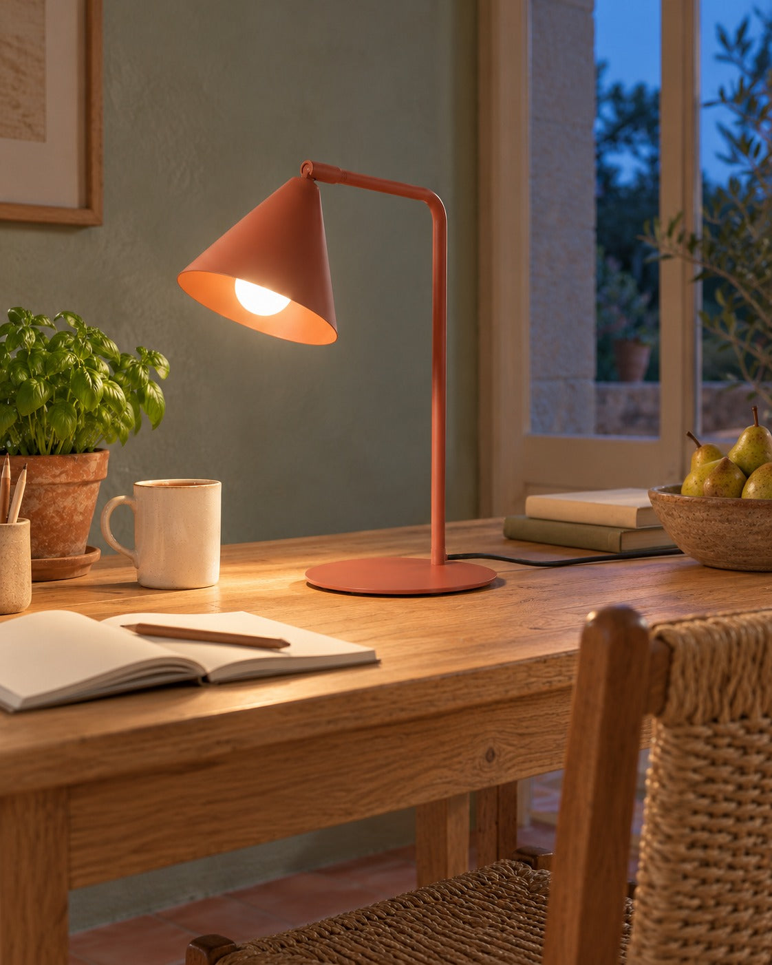 Lampe Nox ocre rouge allumée le soir sur une table de travail dans un bureau